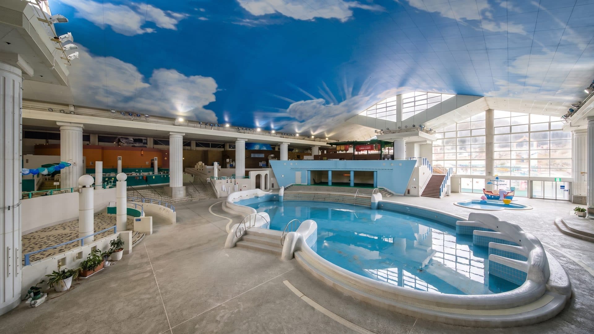 The pool hall at Yunessun in Hakone under its painted sky-and-cloud ceiling