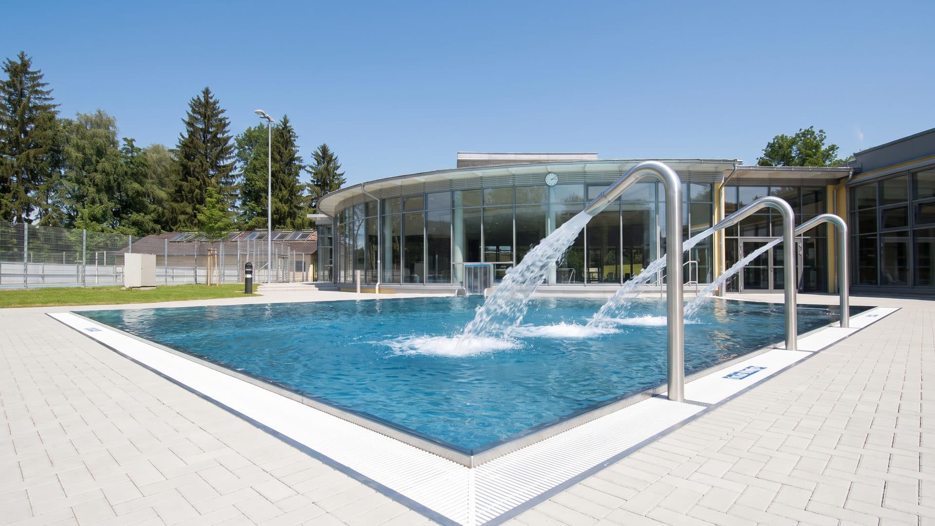 The outdoor pool of the Grünwald leisure park with its water jets before the round glass hall