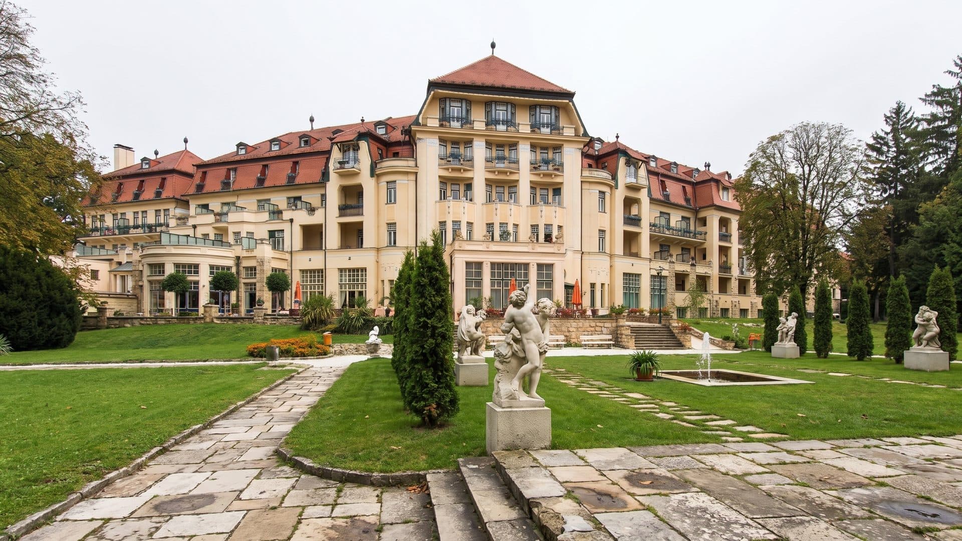 The historic spa house at Piestany behind a formal garden of clipped conifers, statues and lawn