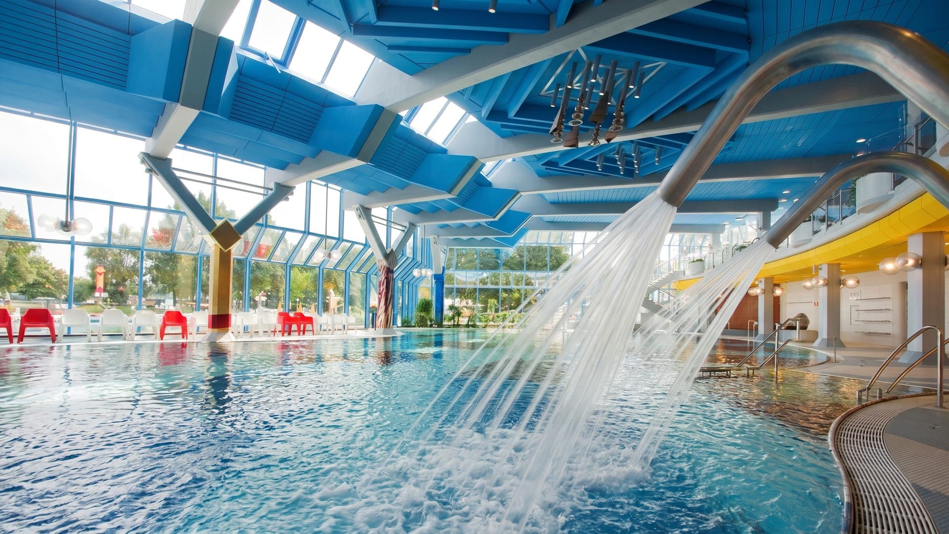 Cascade pouring into the pool under the blue steel roof