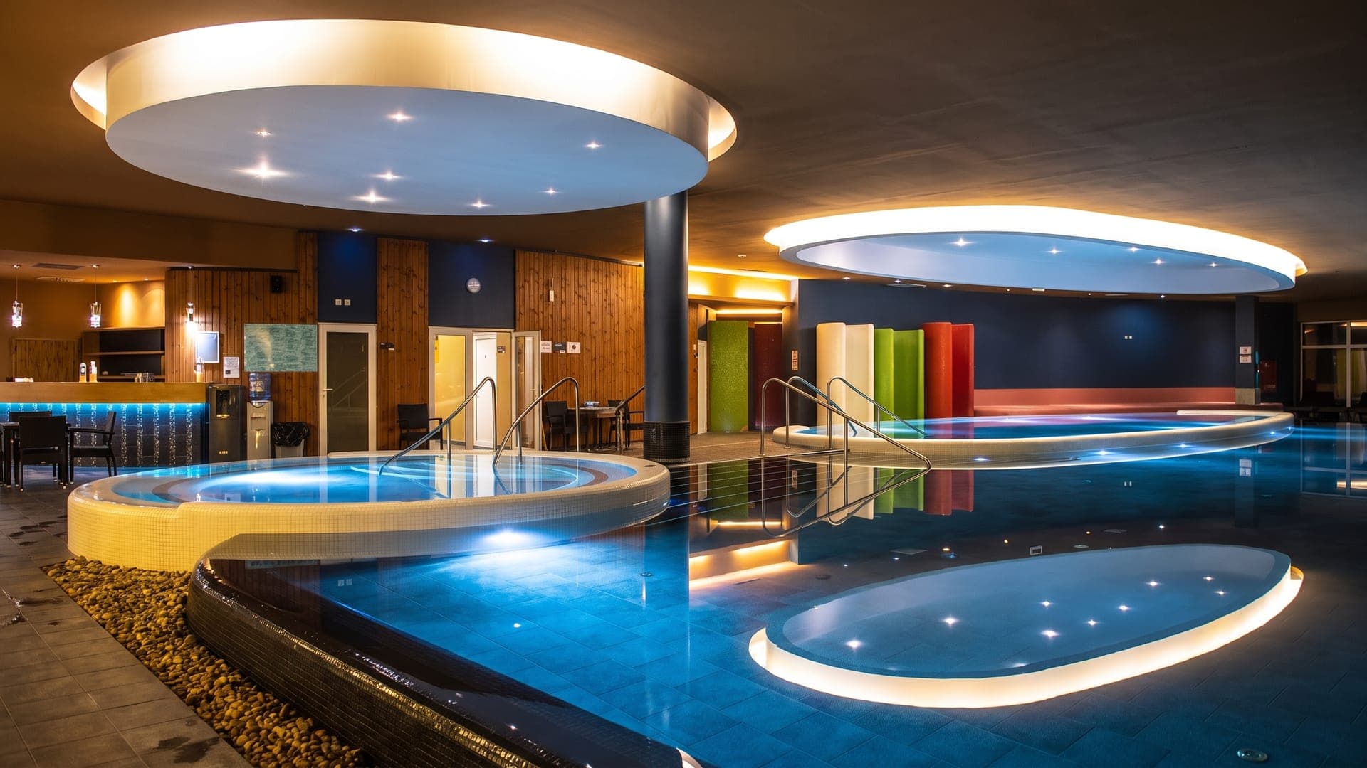 The wellness hall at the Napfenyfurdo Aquapolis in Szeged, its pools under oval lit ceiling coves.