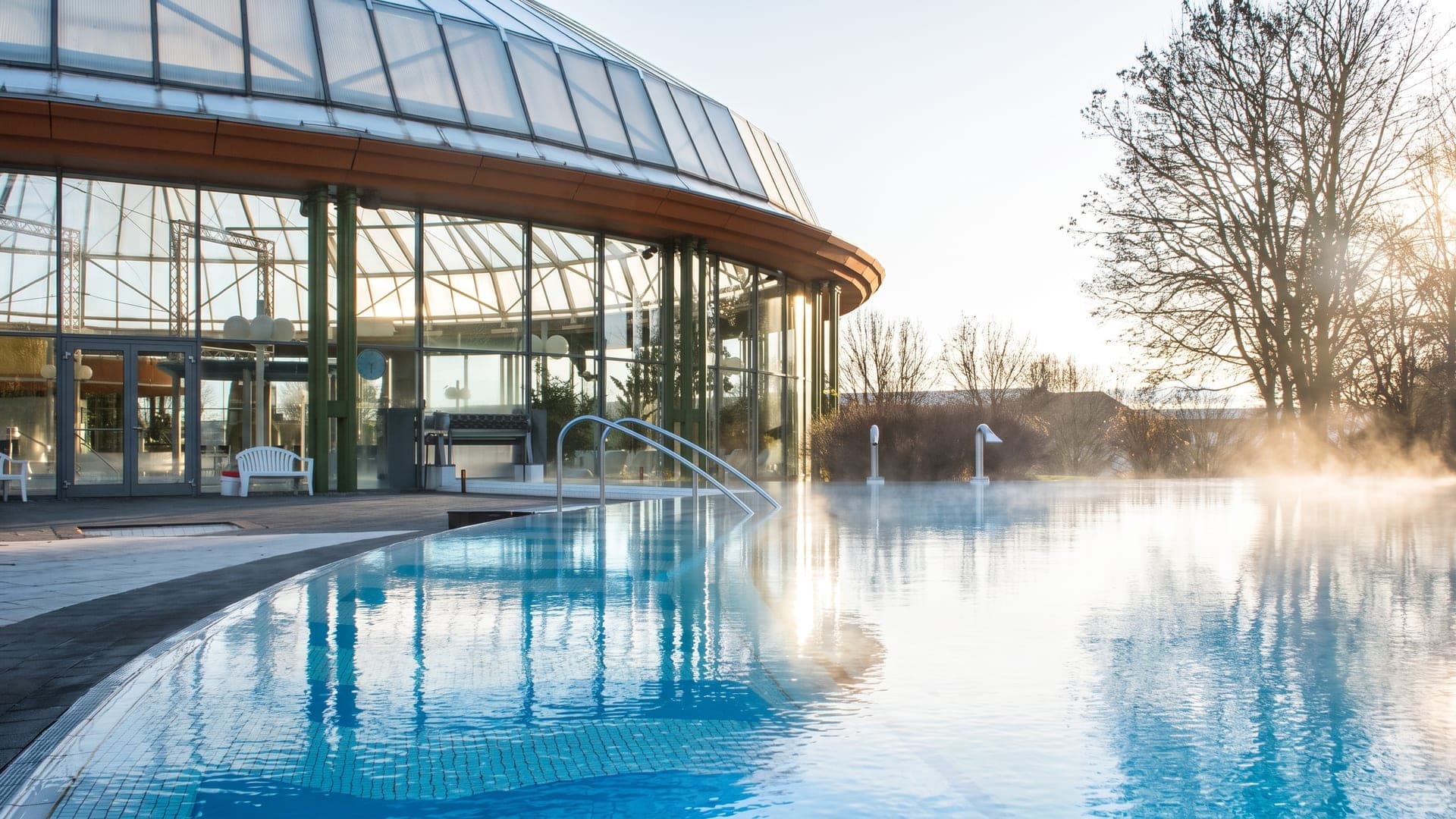The outdoor pool at the Schwaben Therme in Aulendorf, the domed hall reflected in the still water.