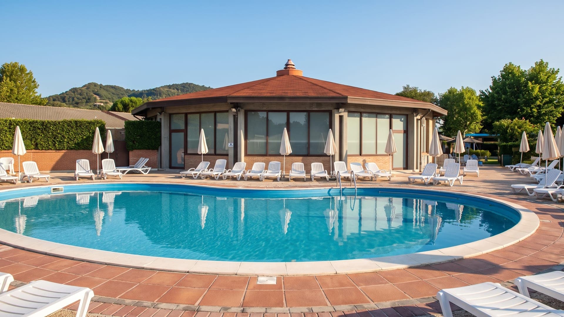 The outdoor thermal pool at La Contea in Battaglia Terme, beside a pavilion with a conical tiled roof.