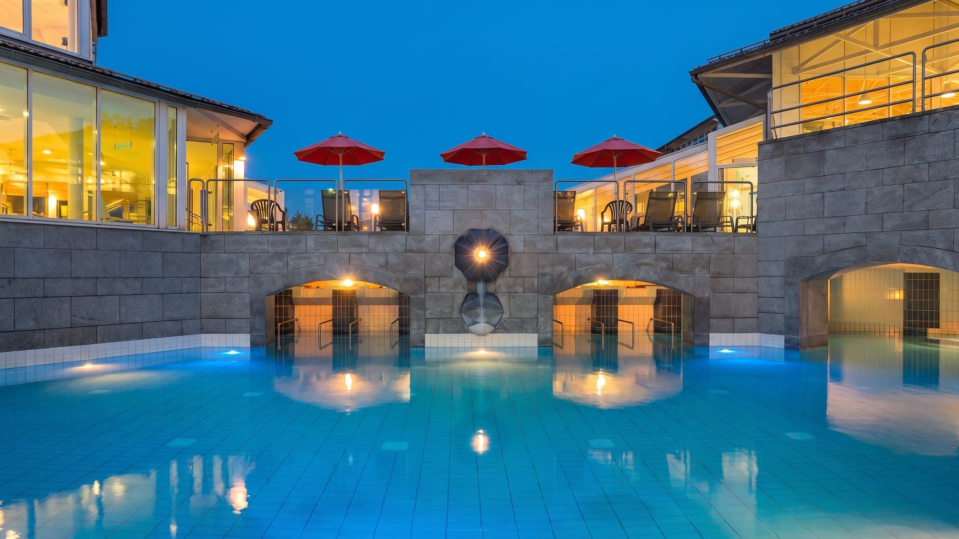The grotto pool at Therme Eins in Bad Fuessing at night, its stone arches lit above the water.
