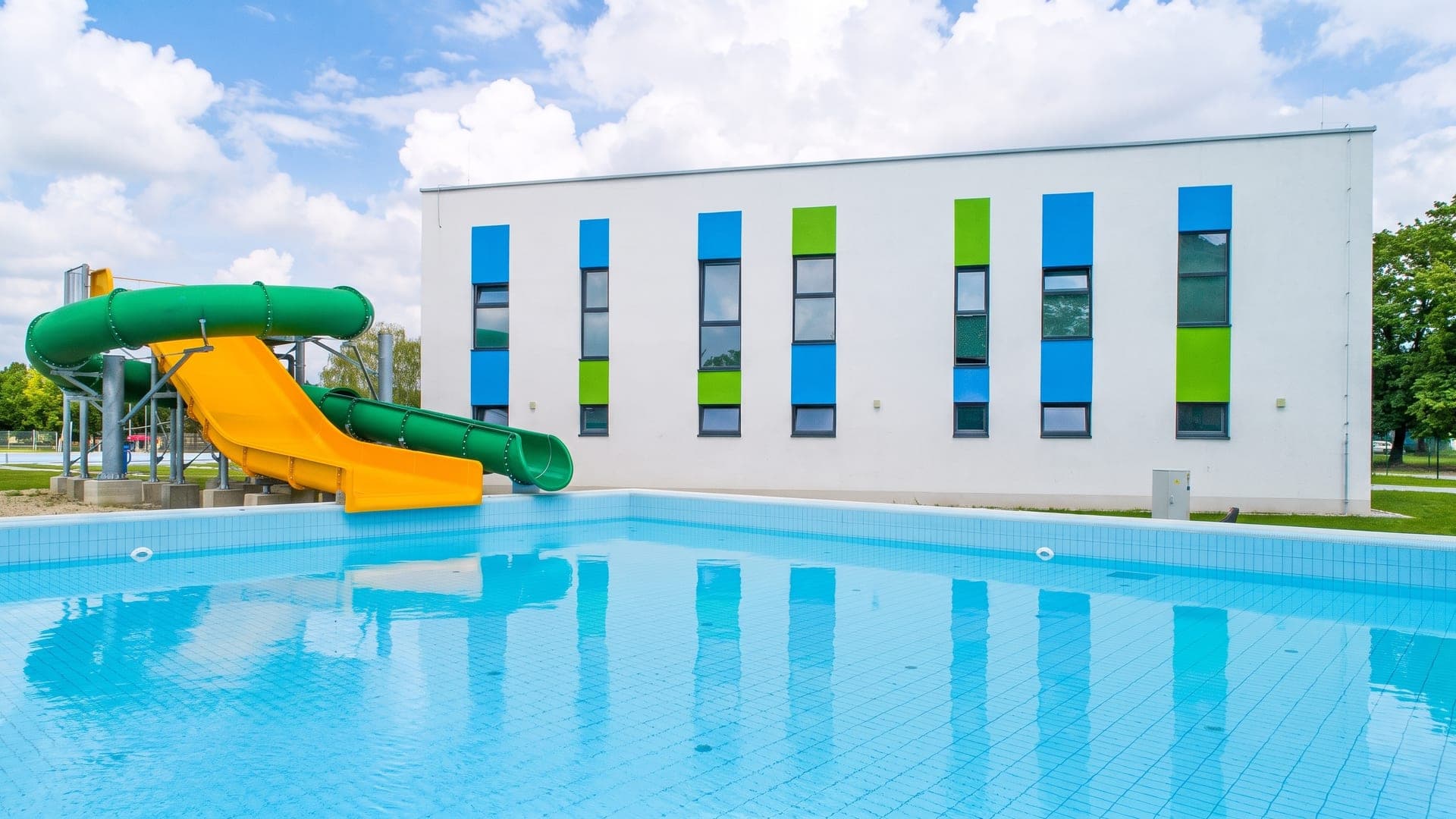 Green and yellow slide beside the blue-and-green panelled building
