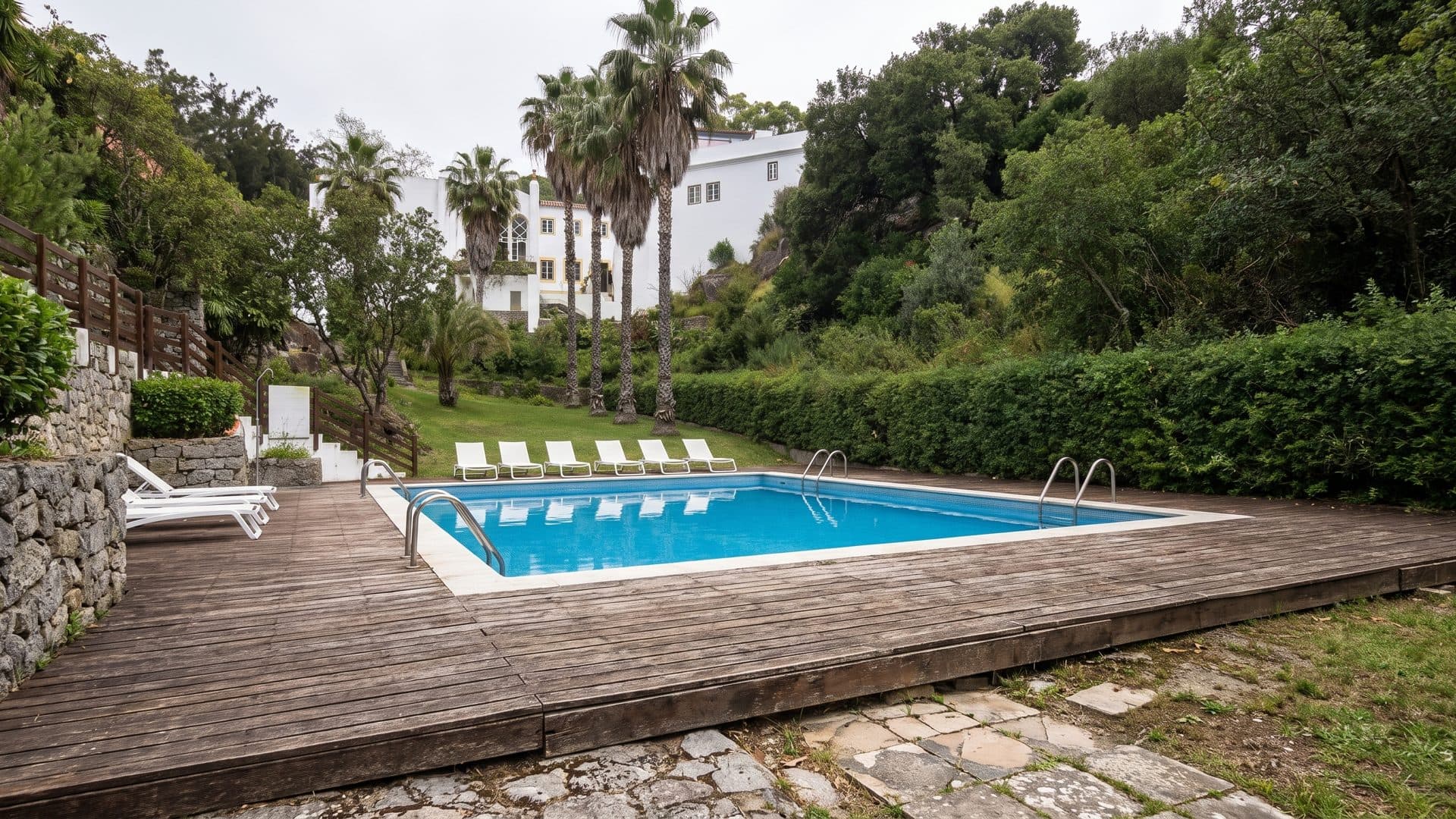 The small blue pool at Caldas de Monchique among palms and greenery, loungers along its edge